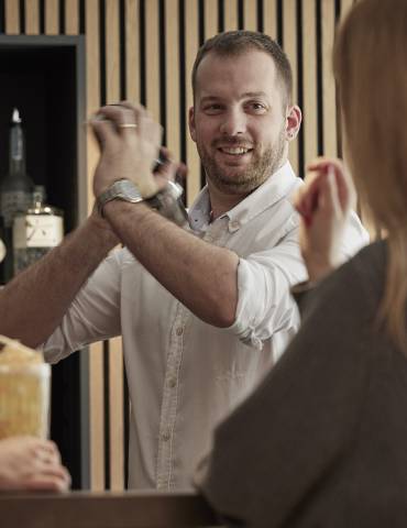 Bar waiter mixes cocktails for two ladies - The Brandstetterhof